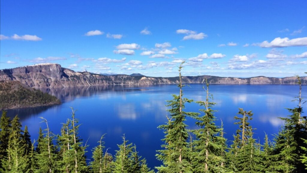 Land Acknowledgement Blue sky white clouds mountains around a lake